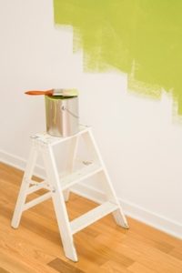 paint can on step ladder next to partially painted wall