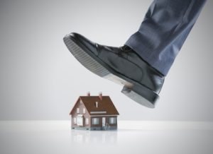 Man's foot about to step on miniature house