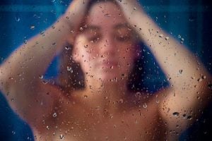 Woman in a shower behind glass
